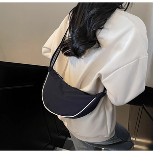 Detail of dark blue crescent canvas bag with striped strap and white contrast piping