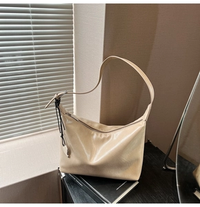 Détail d'un sac porté épaule en cuir plissé beige avec pendentif cœur et bandoulière large