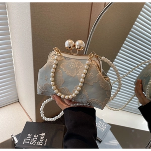 Detail of light blue floral embroidery and pearl clasp on a silk-style handbag