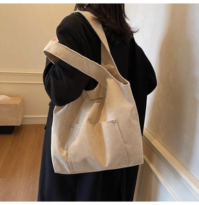 Detail of beige corduroy tote bag with side pocket and silver metal rivet accents