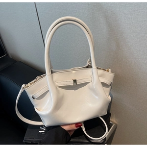 Dettaglio della borsa in pelle lucida bianca con pieghe e fibbia dorata su supporto
