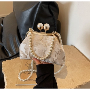 Detail of vintage beige floral jacquard clutch with pearl handles and metal frame clasp