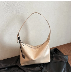Détail du sac hobo crème en cuir brillant avec pendentif en métal en forme de cœur