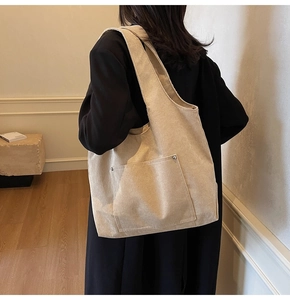 Detailed texture of beige corduroy tote bag with side silver rivet accents on strap