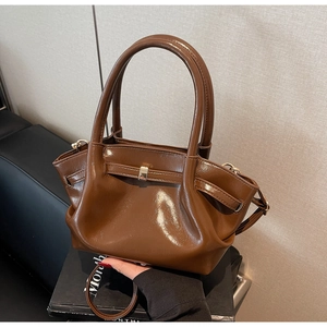Dettaglio della borsa tote in pelle verniciata marrone con pieghe e fibbia in metallo