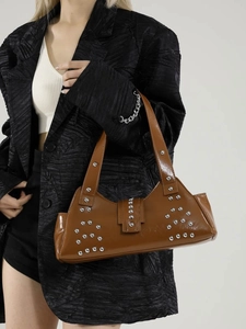 Bruine tote bag met klinknagels van glanzend kunstleer gedragen door model