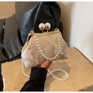 Detailed embroidery on champagne jacquard evening bag with large pearl clasp closure