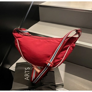 Close-up of red nylon crescent bag with a blue and white striped adjustable strap