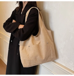 Detail of beige corduroy tote bag showing metal rivets and ribbed texture on the shoulder strap