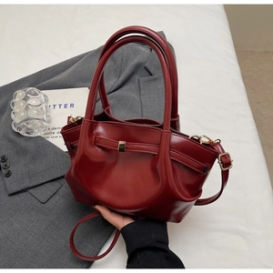 Dettaglio della borsa tote rosso intenso lucido con fibbia metallica e trama in pelle pregiata