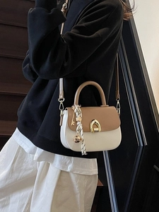 Chic two-tone saddle bag with horse-bit buckle and silk scarf accessory on crossbody model