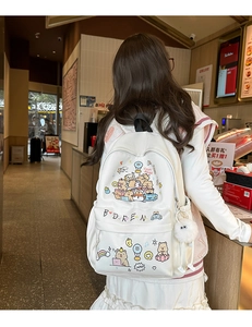 Detail of white canvas backpack featuring cute capybara cartoon print and plush ball pendant