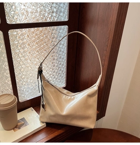 Détail d'un sac sous le bras beige brillant avec un charmant pendentif en forme de coeur