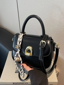 Classic black saddle handbag with gold horseshoe clasp and decorative key charms