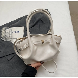 Dettaglio della borsa tote bianco panna con fibbia dorata su sfondo minimalista