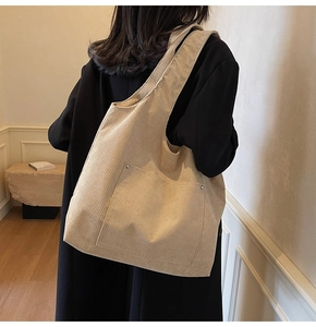 Detail of beige corduroy tote bag with large capacity and decorative metal buckle