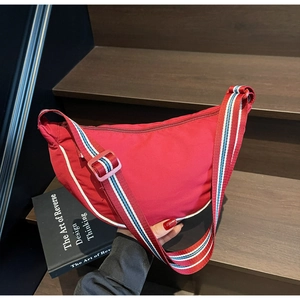 Detail of red crescent canvas bag with adjustable striped shoulder strap on a staircase