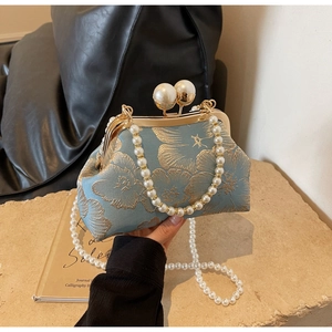Detail of light blue embroidered bag with floral texture and large pearl clasp