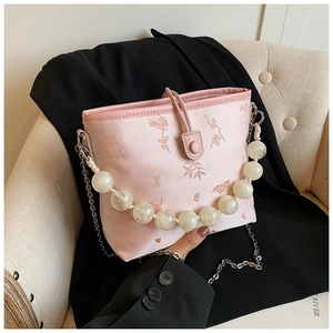 Détail du sac seau en satin rose avec broderie florale et grande poignée en perles