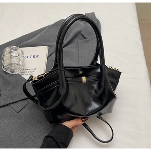 Dettaglio della borsa a mano nera lucida con fibbie dorate e tracolla in pelle elegante