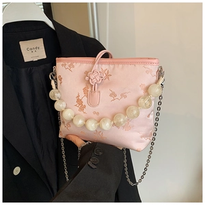 Détail d'un sac seau en satin rose avec broderie florale et anse à grosses perles