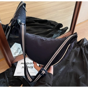 Detail of navy canvas dumpling bag with adjustable tricolor striped shoulder strap