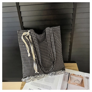 Detail of gingham tote bag featuring white lace trim and a side-tied lace bow accent