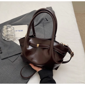 Dettaglio borsa tote in pelle lucida marrone scuro con fibbia in metallo e tracolla sottile