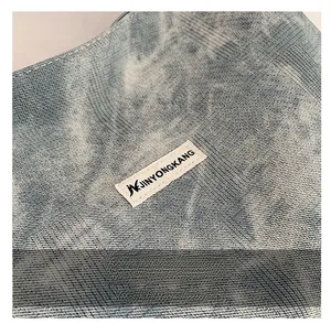 Macro shot of washed blue denim fabric texture and white brand label on the dumpling bag