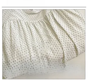 Detail of white polka dot fabric with pleated texture and Romance ribbon label