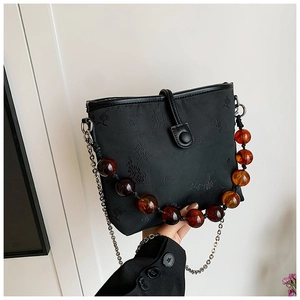 Détail du sac seau noir brodé avec poignée en perles ambre et chaîne argentée