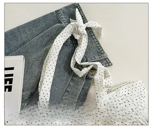 Close-up of adjustable tie-up shoulder straps on a black and white polka dot tote bag