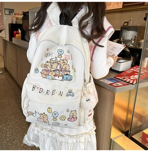 Detailed view of white canvas capybara backpack featuring cute cartoon prints and plush ball