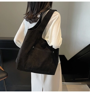 Detailed view of black corduroy tote bag featuring vertical stripes and front patch pocket