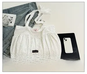Detail of white polka dot tote bag with bow shoulder strap and Romance embroidery