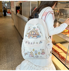 Close-up of white cartoon backpack with Capybara prints and plush charm in a cafe setting