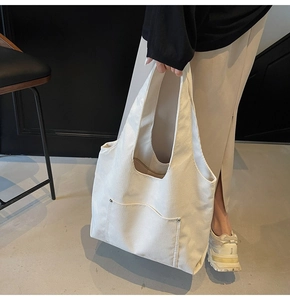 Detail of off-white corduroy tote bag featuring vertical stripes and front pocket with rivets