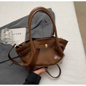 Dettaglio borsa shopper marrone lucida con doppi manici e tracolla sottile rimovibile