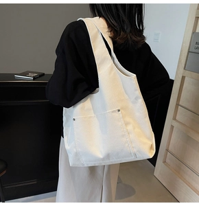 Detail of off-white corduroy tote bag with large front pocket and silver metal rivets