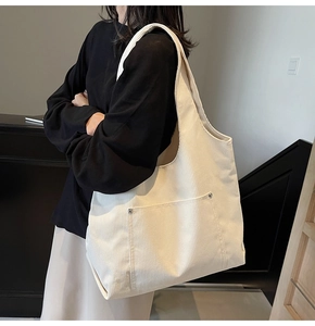 Detail of off-white corduroy tote bag showing ribbed texture and metal rivet pocket