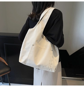 Detail view of cream corduroy tote bag showing vertical rib texture and metal rivets
