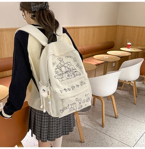 Close-up of cute cartoon animal illustrations and plush charm on a beige canvas backpack