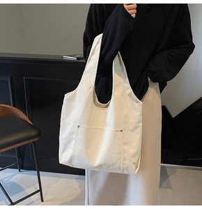 Detail of off-white corduroy tote bag showing textured vertical stripes and metal rivet pocket