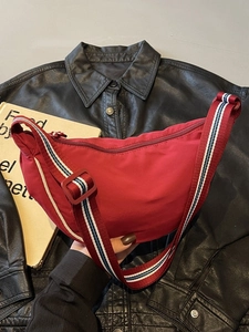 Red crescent nylon crossbody bag with striped wide strap and minimalist metal zipper