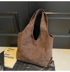 Detailed close-up of dark brown corduroy tote bag texture with metal rivet pocket