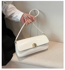 Detail of cream-white leather underarm bag featuring a metallic gold semicircular buckle