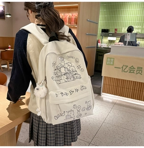Detail of cute hand-drawn cartoon prints and plush ball charm on a beige casual backpack