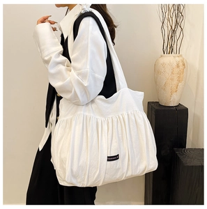 Detail of white pleated tote bag showing fabric texture and Romance woven label
