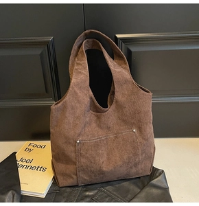 Close-up of brown corduroy tote bag featuring stitched front pocket and soft texture