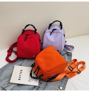 Detailopname van mini nylon rugzakken in rood, paars en oranje met koordgrepen en metalen gesp